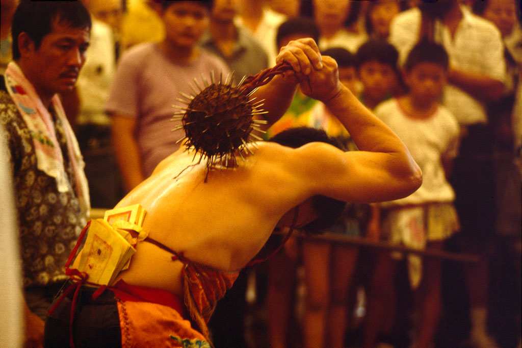 A man beating himself with a mace with spikes